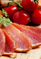 Pork smoked ham and tomatoes on the board, selective focus