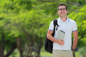 Fototapeta premium smiling college student with backpack holding a tablet