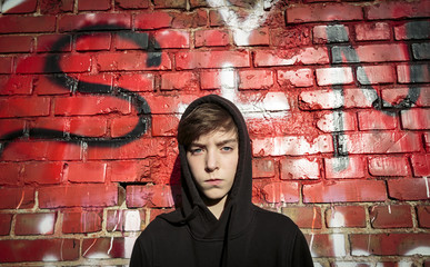 portrait of a serious teenage boy in front of a red graffiti
