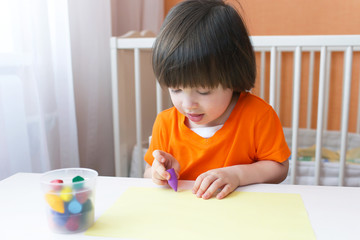 Lovely 2 years boy painting with wax pencils