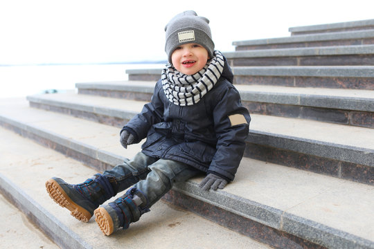 Fashionably dressed little boy sitting on stairs outdoors in spr