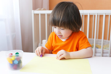 Lovely 2 years boy paints with wax pencils