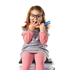 Surprised little girl with glasses sitting on books