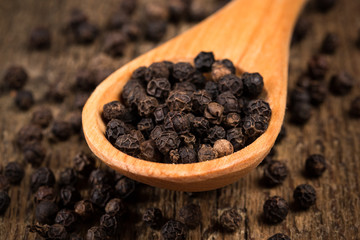 black pepper on wooden spoon