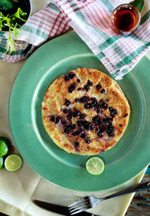 blueberry pancake on green plate served with maple syrup