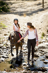 female child riding pony happy with mother  horse instructor