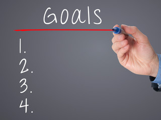 Businessman is writing goals list, planning on whiteboard.