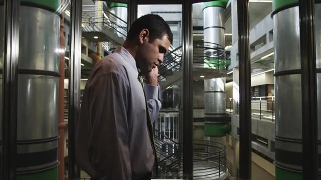 MS Man talking on mobile phone in modern elevator in office building / Orem, Utah, USA