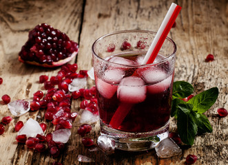 Fresh red juice cocktail with pomegranate seeds, mint and ice, s