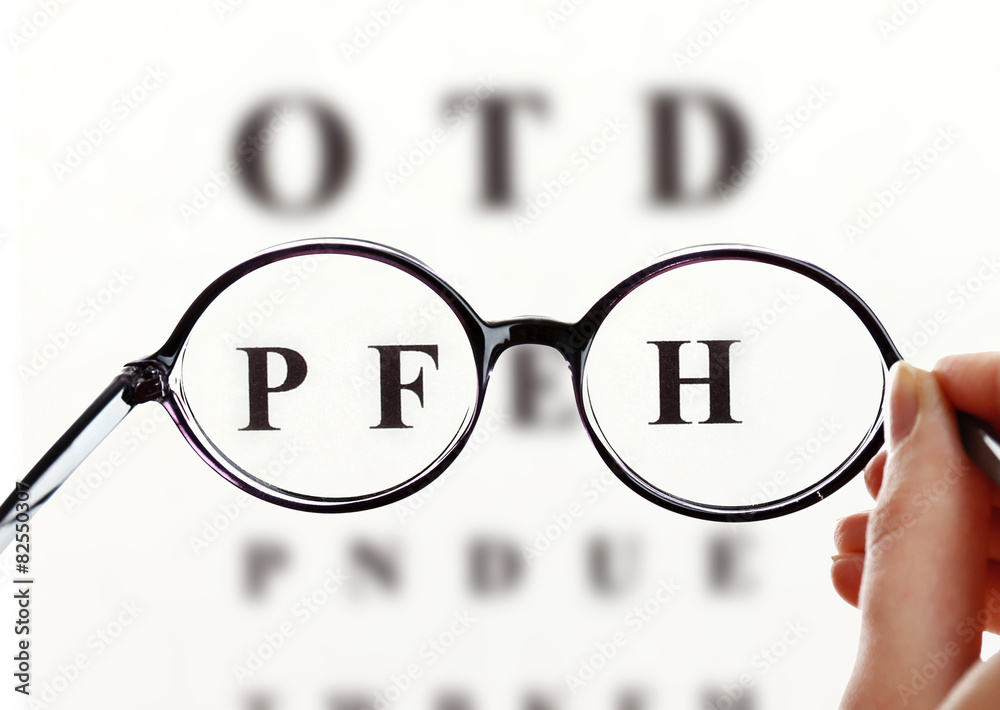 Wall mural Eye glasses on eyesight test chart background