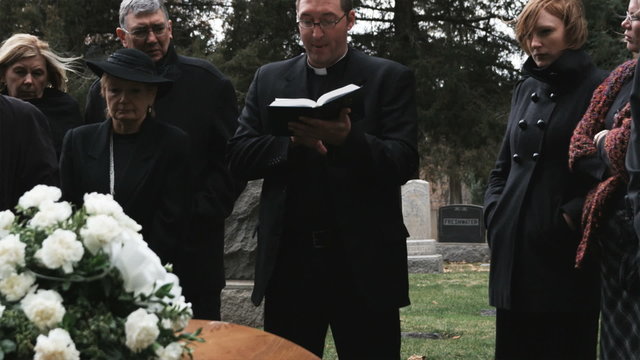 priest giving a eulogy at a funeral