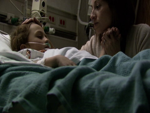 Woman caressing child in hospital bed