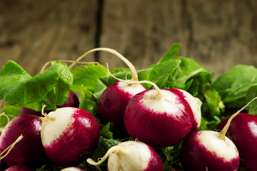 Fresh radishes with leaves on a wooden table, selective focus