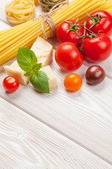 Pasta, tomatoes, basil on wooden table