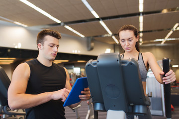 woman with trainer exercising on stepper in gym