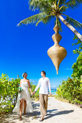 Happy bride and groom having fun on a tropical beach under the p