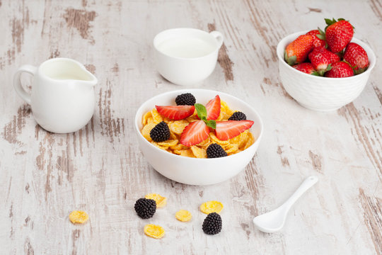 cornflakes with berries in a bowl and milk for breakfast, close-
