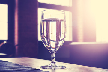 Vintage toned glass of water against window.