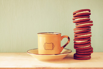 stack of cookies over wooden table next to cup of coffee