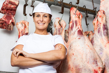 Butcher Standing Against Meat Hanging In Butchery