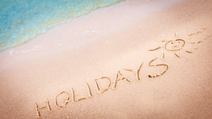 The word holidays written in the sand on a beach