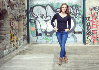 Young and beautiful girl posing against graffiti wall