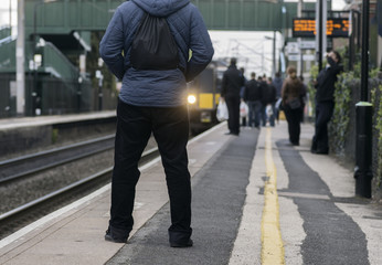 Man standing on station platform as train pulls in