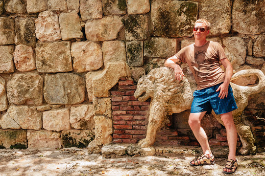 Young Man In Shorts Leaning Against Ancient Stone Wall