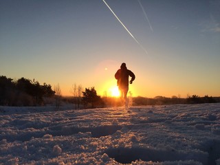 Silhouette of a runner on snowy winter morning