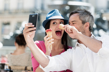 couple taking a selfie while eating an ice cream on a terrace 