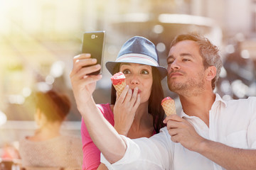 couple taking a selfie while eating an ice cream on a terrace
