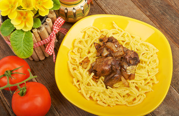 Noodles with fried liver and tomatoes on an old vintage table