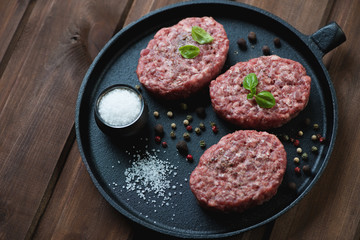 Frying pan with raw beef cutlets and different spices