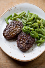Close-up of beef cutlets with green beans on a plate