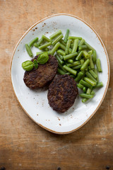 Beef cutlets with beans, rustic wooden background, above view