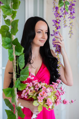 The girl in a pink dress smiling next to the grape vine