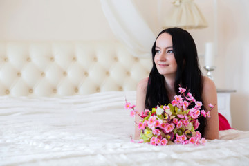 Obraz na płótnie Canvas Girl with flowers on the bed