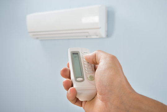 Man Adjusting Temperature Of Air Conditioner