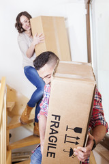 young couple carrying the boxes in new house