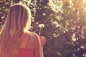 Woman blowing a dandelion - Powered by Adobe