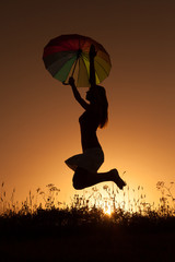 Silhouette of happy woman jumping in sunset