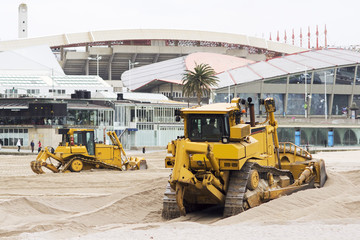 yellows excavators on the city  beach working sand moving