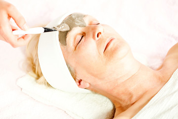 Beauty skin treatment, beautician applying clay mask