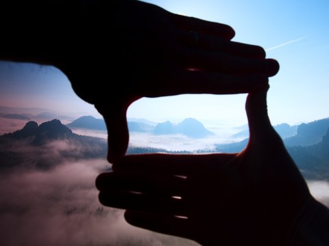 Close up hands make frame gesture Blue misty valley in mountains