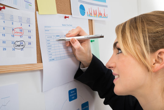 Businesswoman Writing On Weekly Time Sheet