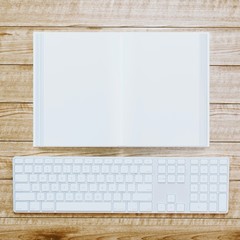 blank opened book and keyboard on wooden background.