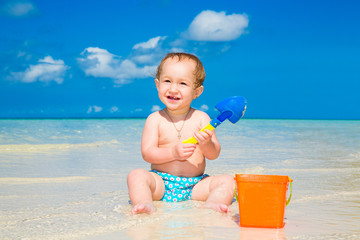 A little kid having fun on a tropical beach. Summer vacation con