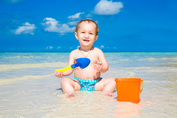 A little kid having fun on a tropical beach. Summer vacation con