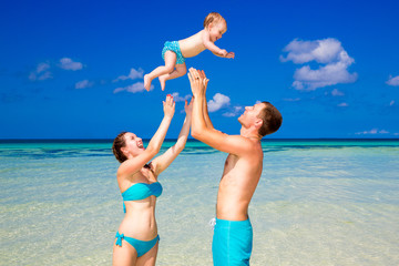 Happy father mother and child having fun on a tropical beach. 