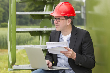 Architect Holding Blueprints While Using Laptop